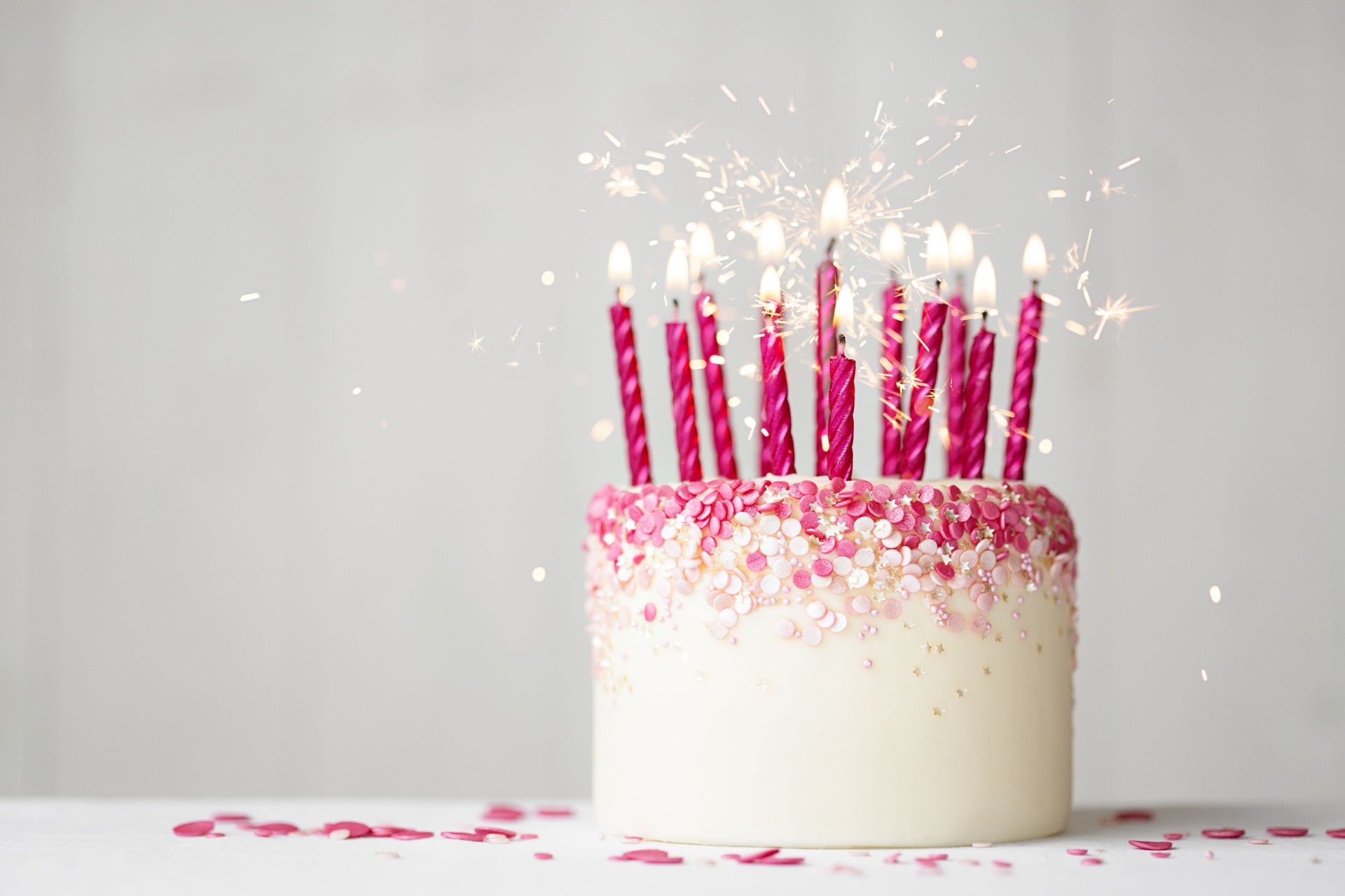 Pink celebration birthday cake with pink birthday candles and sparklers